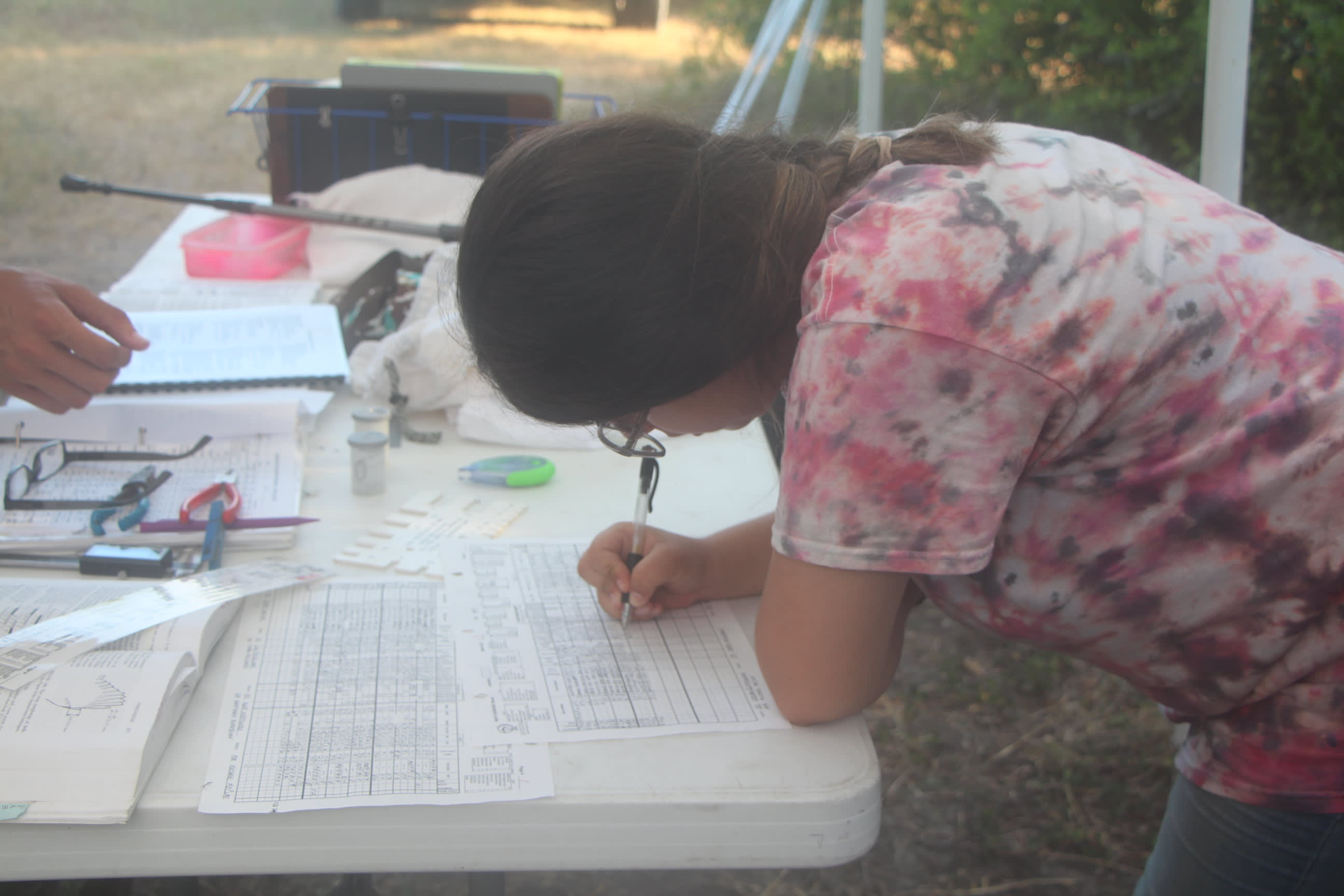 Student bent over table writing data on the datasheet.