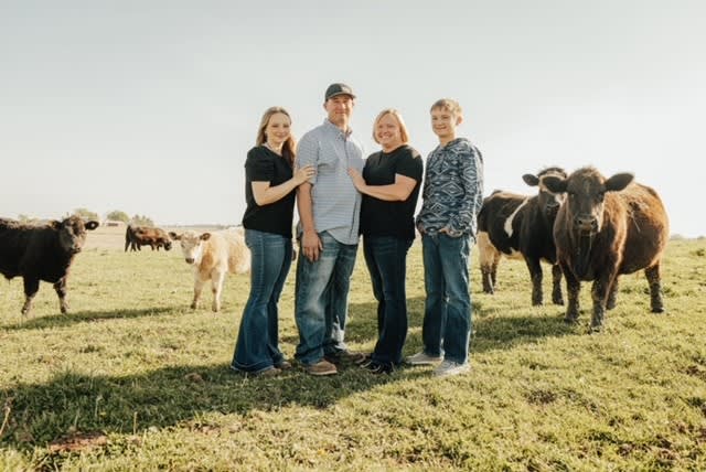 The Barton family standing in a field with steer