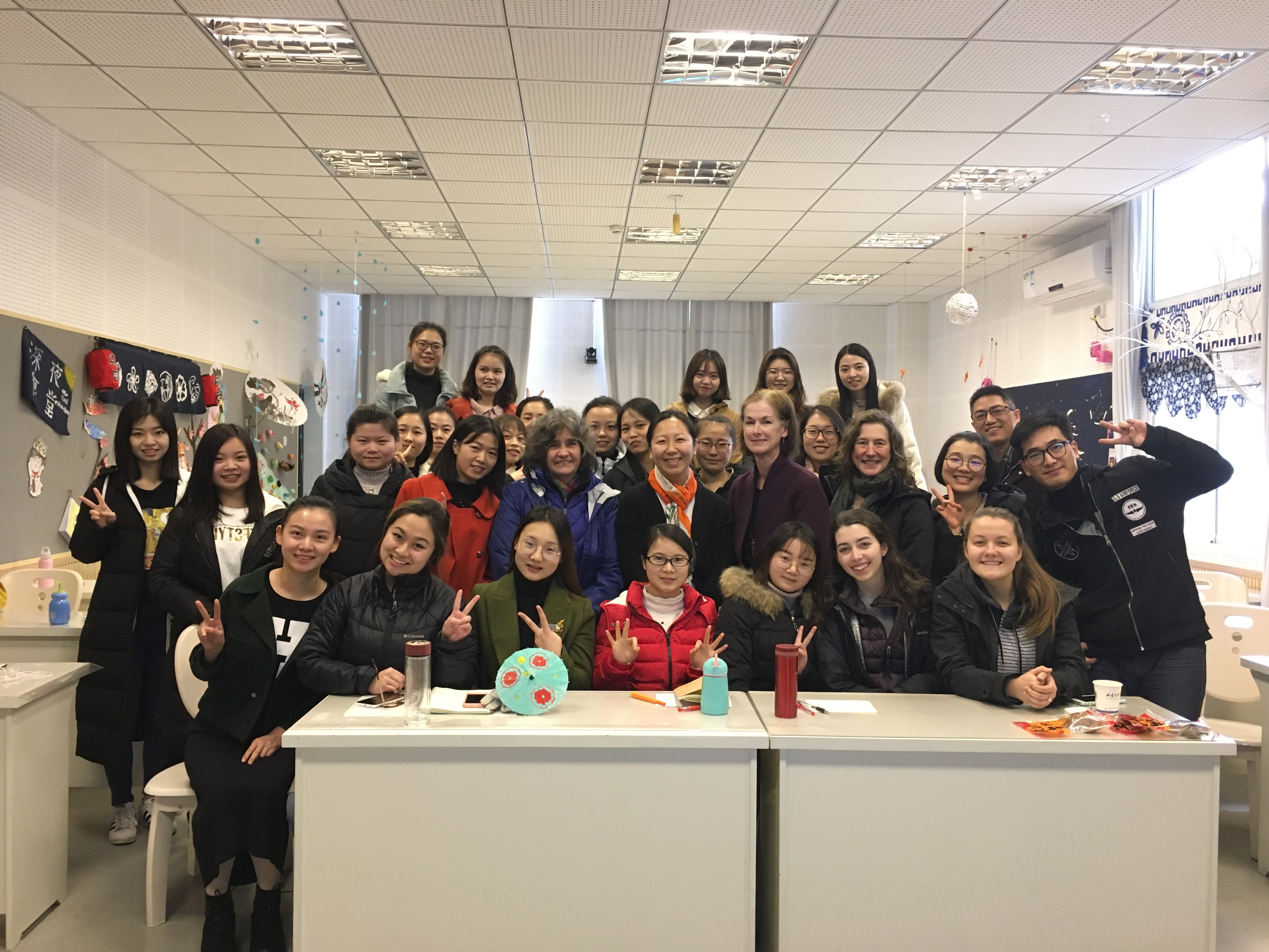 A large group of faculty and students from Western and Southwest University in Chongqing, China pose at a desk.