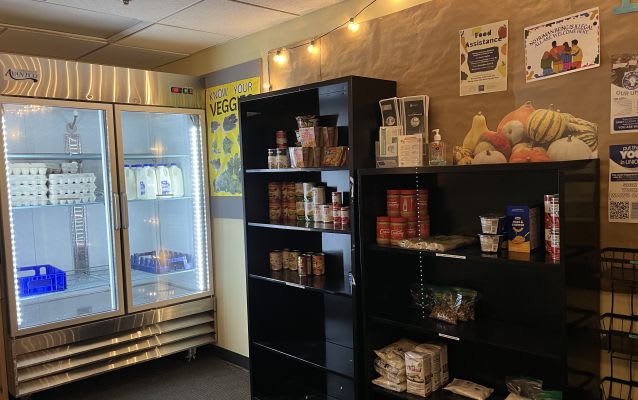 One of the WHOLE food pantries on campus with a large refrigerator and many shelves with canned goods.