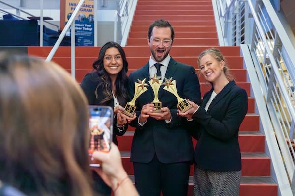 Three business students holding their "Golden Pitch" awards
