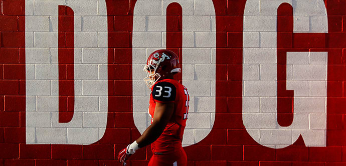 Fresno State Football player walking next to a wall with the words 'DOG' on gameday