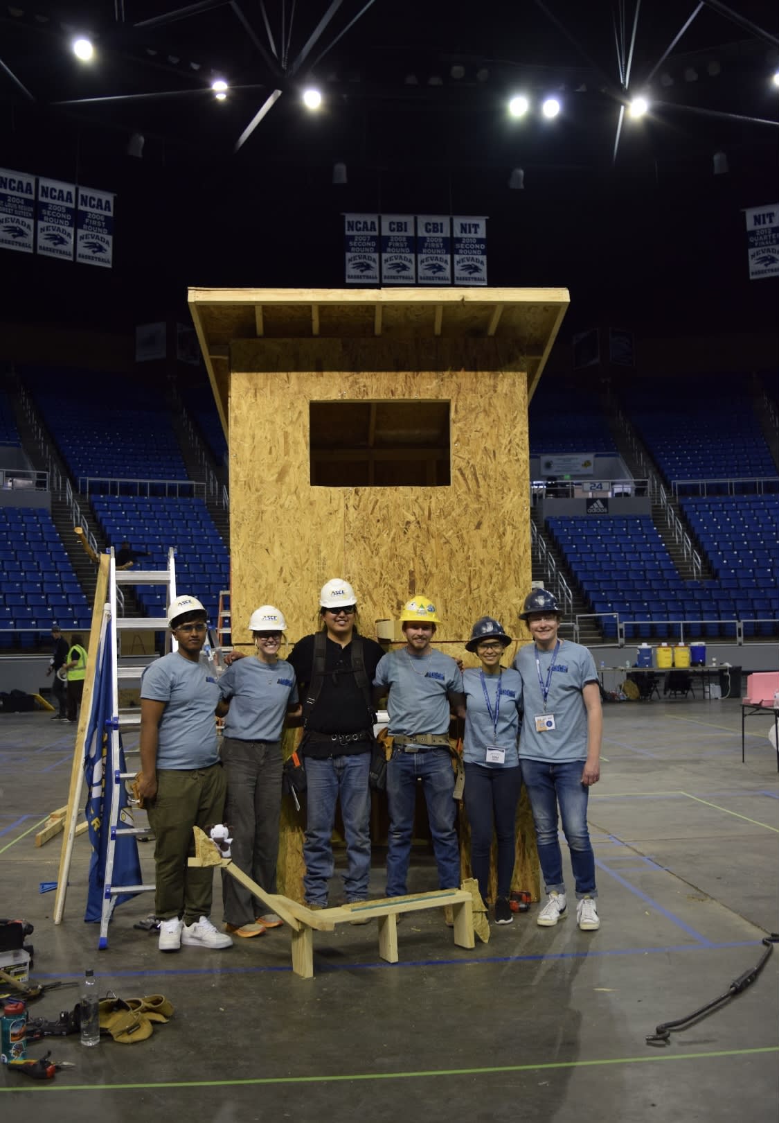 A group of people standing in front of a wooden structure

Description automatically generated