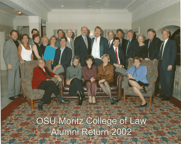 Group of people standing and sitting smiling at a camera during their alumni reunion