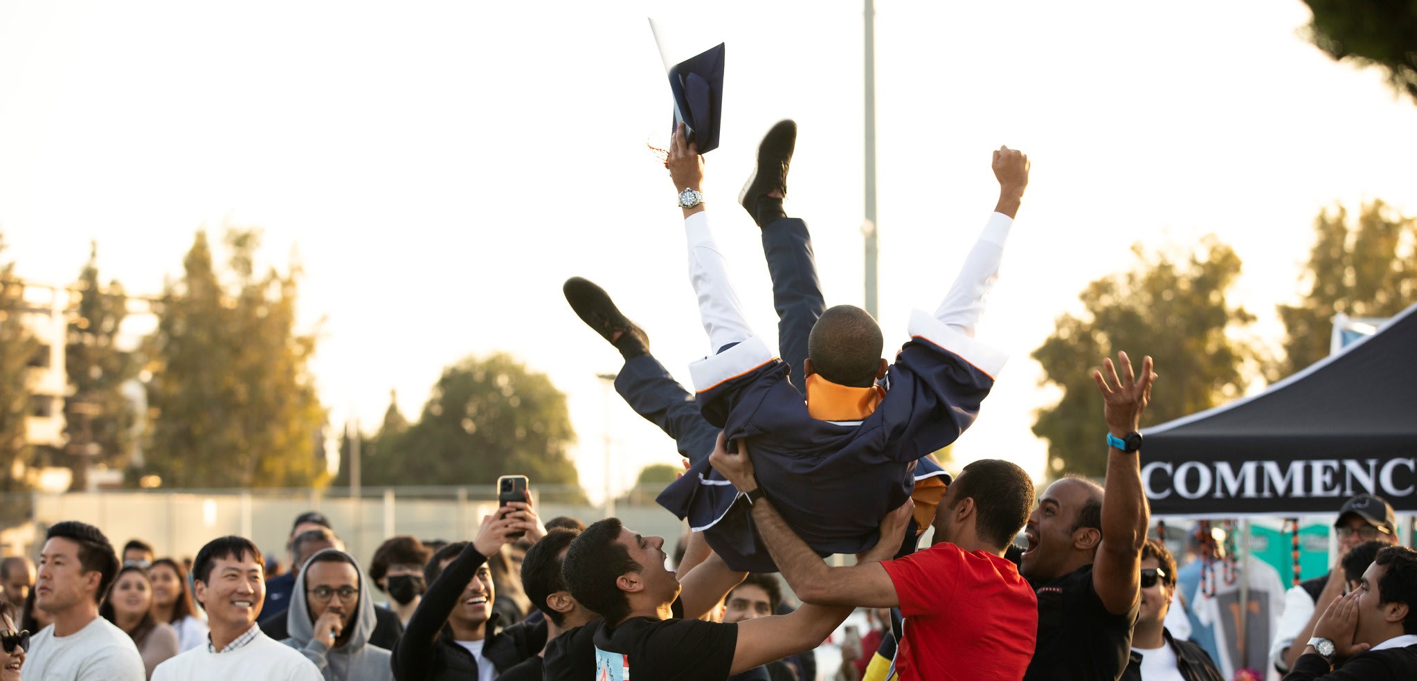 student being thrown into the air by his family after walking the stage at commencement