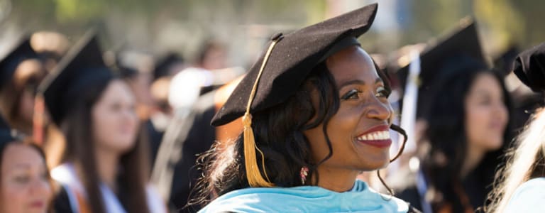 woman in graduation cap and gown smiling