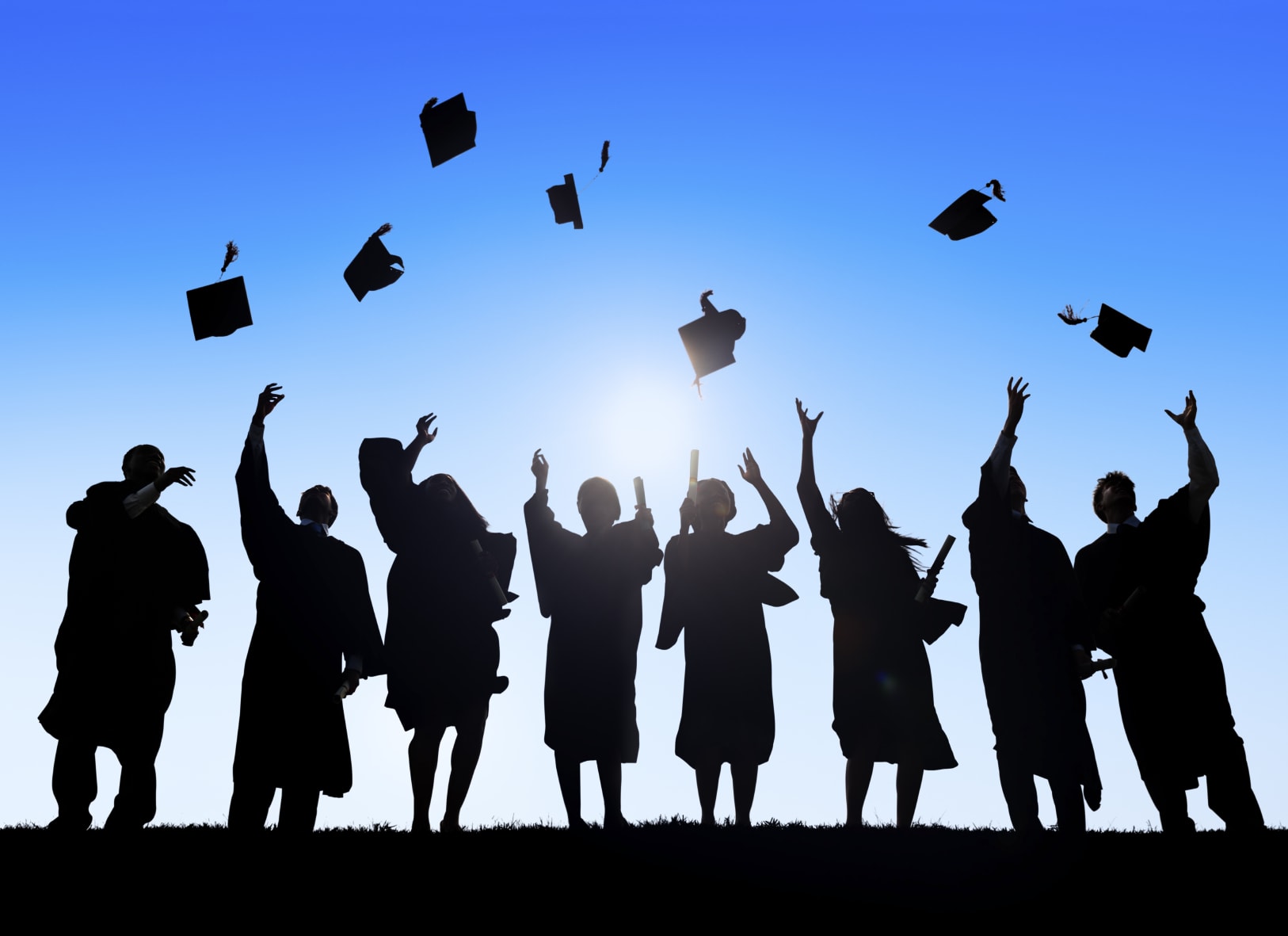 A image showing a silhouette of graduating students tossing their caps into the air.