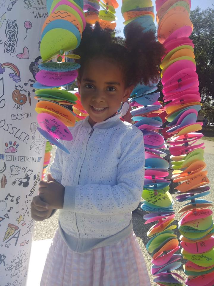 Young girl standing in front of the Peace Pole