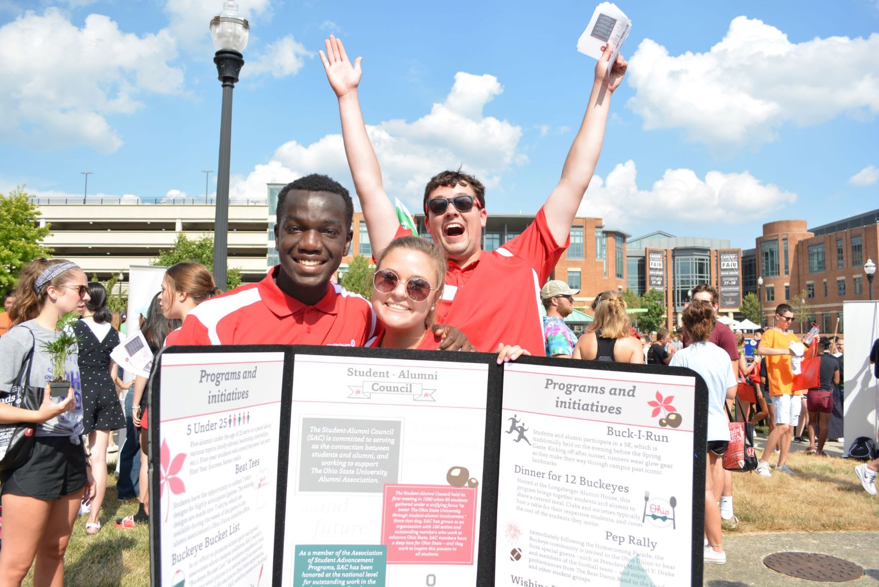 Three council members behind a programs and initiatives trifold