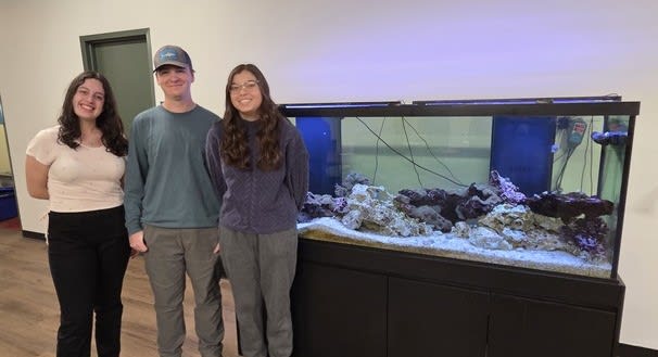 The Three Student Members of Aquarium Club posing in front of the tank.