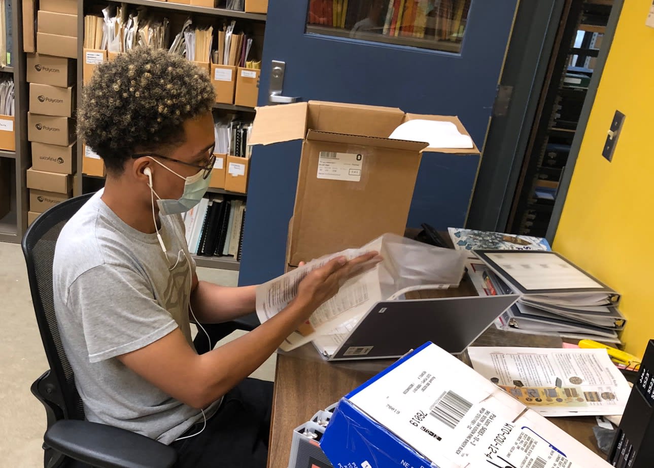 Intern sorting through papers and materials while siting at a desk