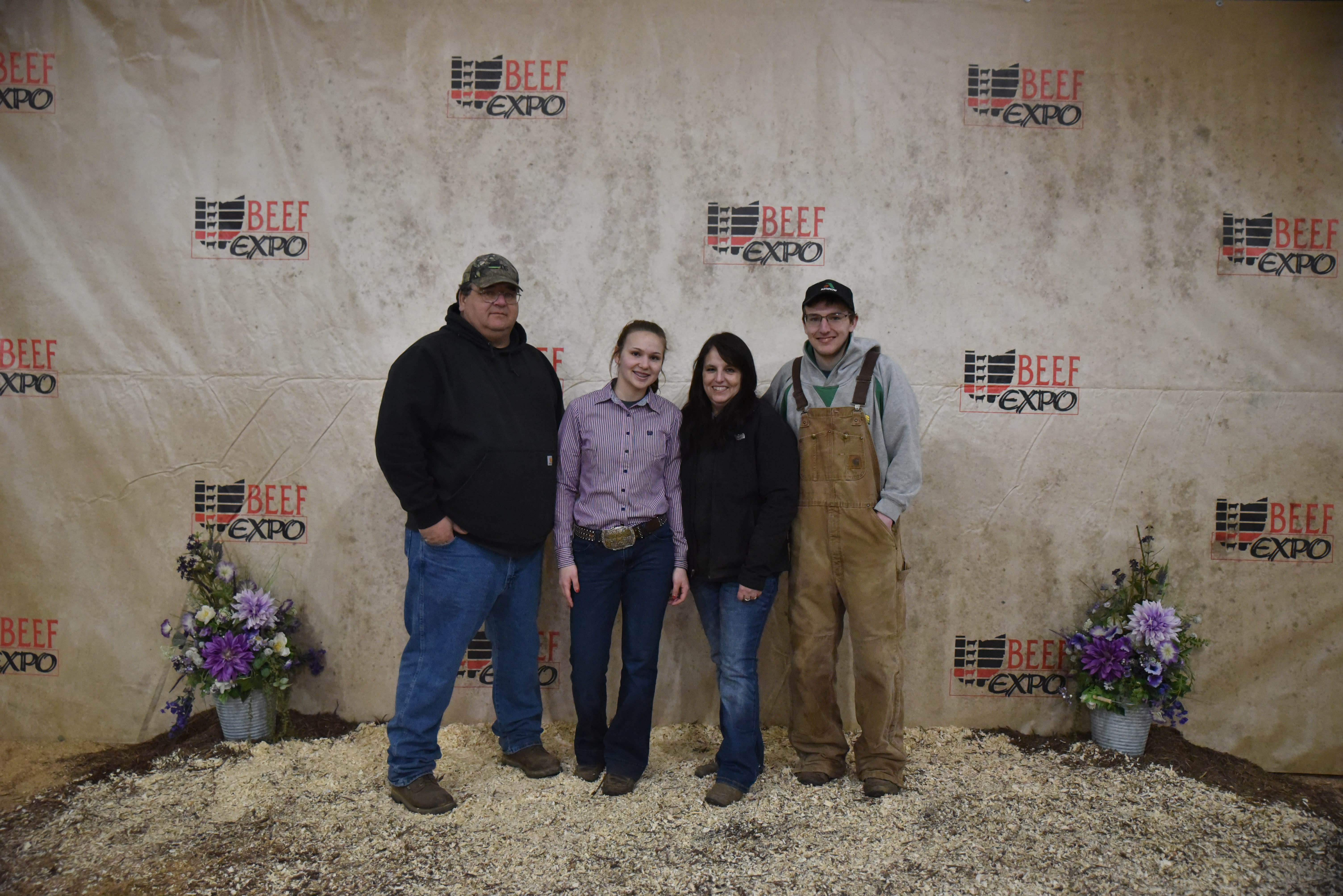 Four members of the Hemlke Family stand together before the Beef Expo backdrop