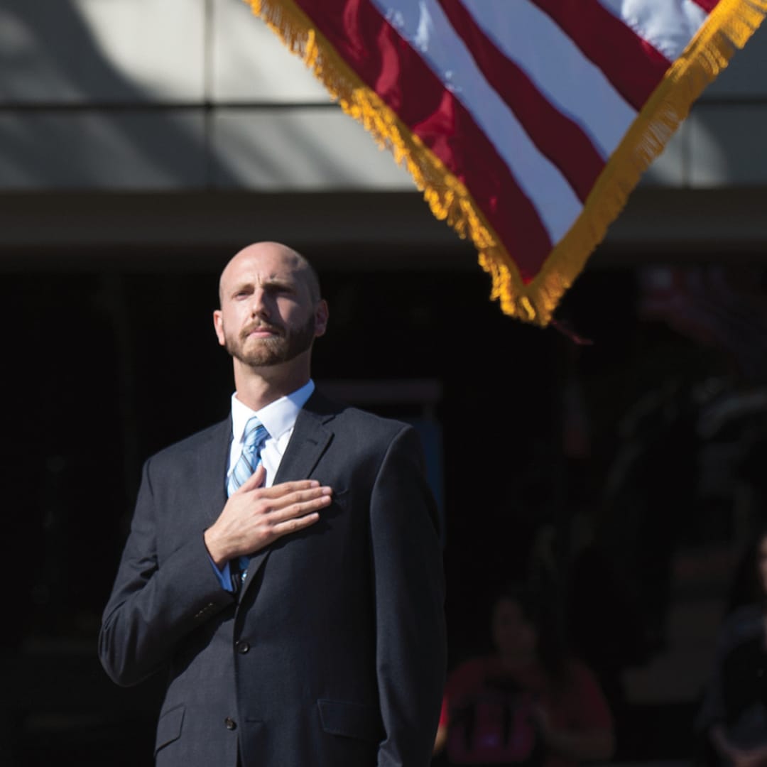 A person in a suit holding a flag

Description automatically generated with medium confidence