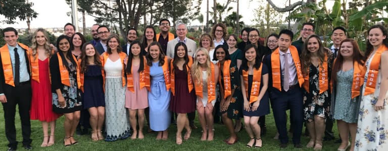 3 rows of 10 students standing outside wearinggraduation sashes 