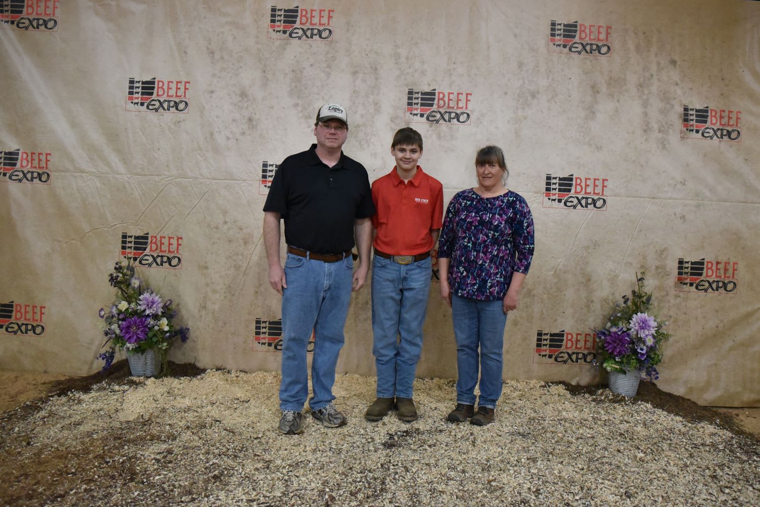 Three members of the Kardotzke Family stand together in front of the Beef Expo's backdrop