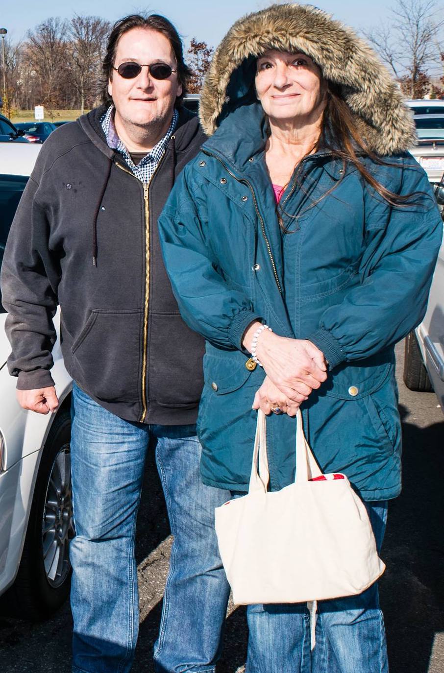 Man and woman smiling while standing next to each other in a parking lot