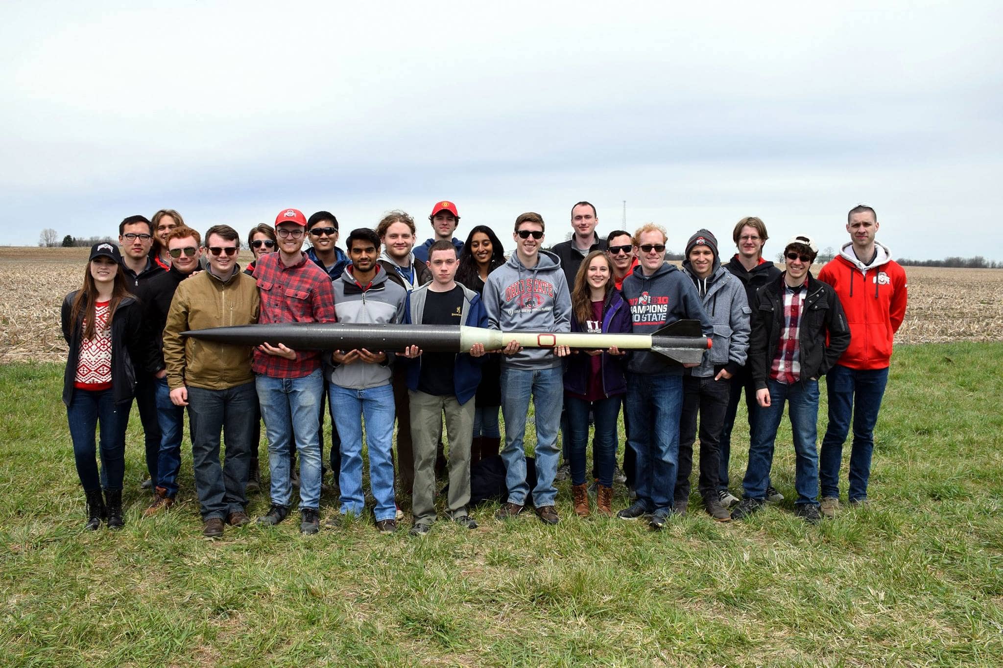 Another group of students holding a black and tan model rocket