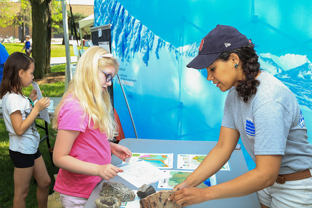An individual works with a young girl, teaching her about the Buckeye Ice Campaign