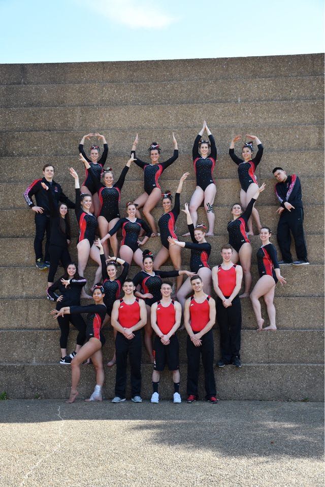 The Club Gymnastics team, staggered standing on steps. They are forming a heart shape with where they stand 