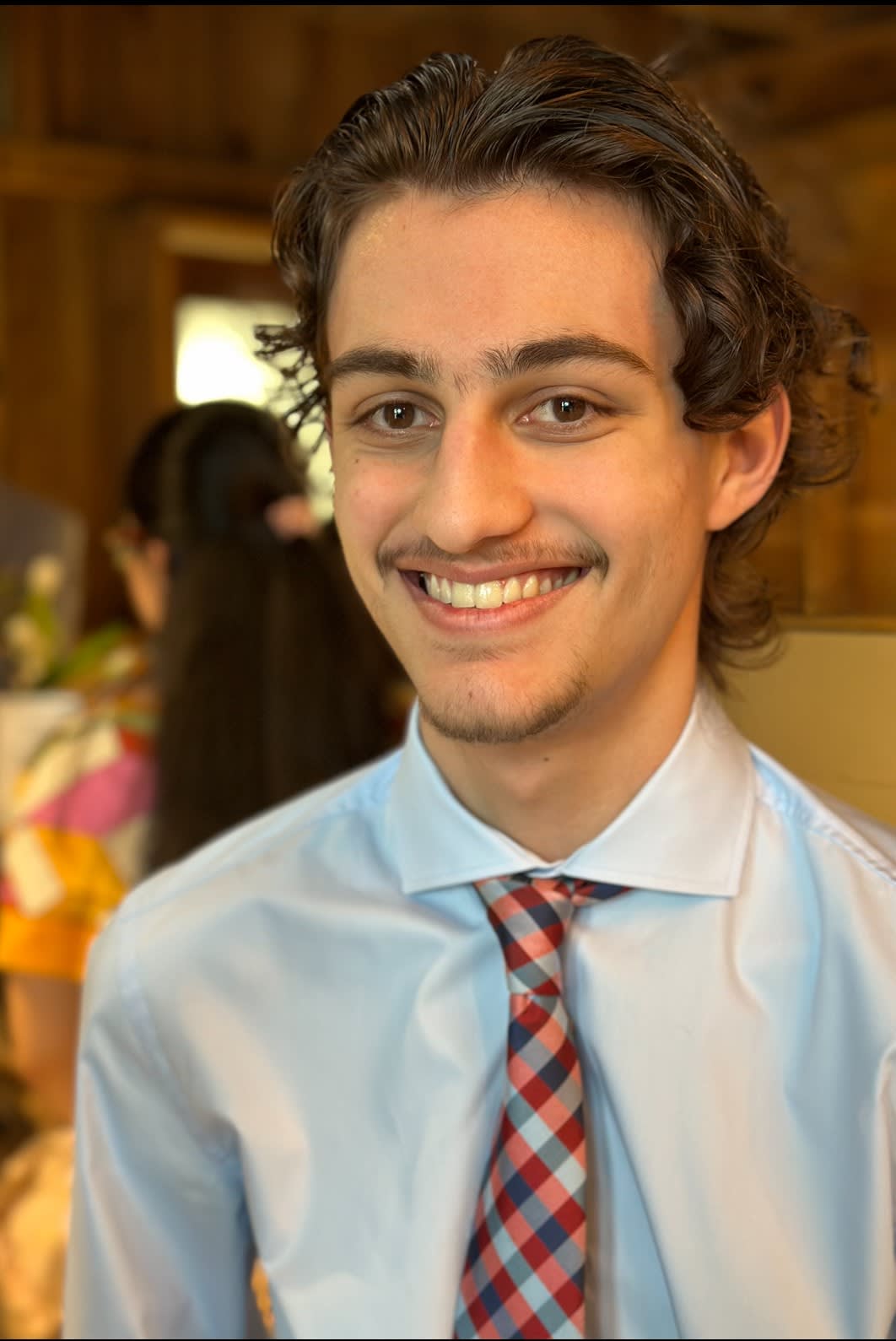 Individual sitting down smiling for a photo at a wedding reception