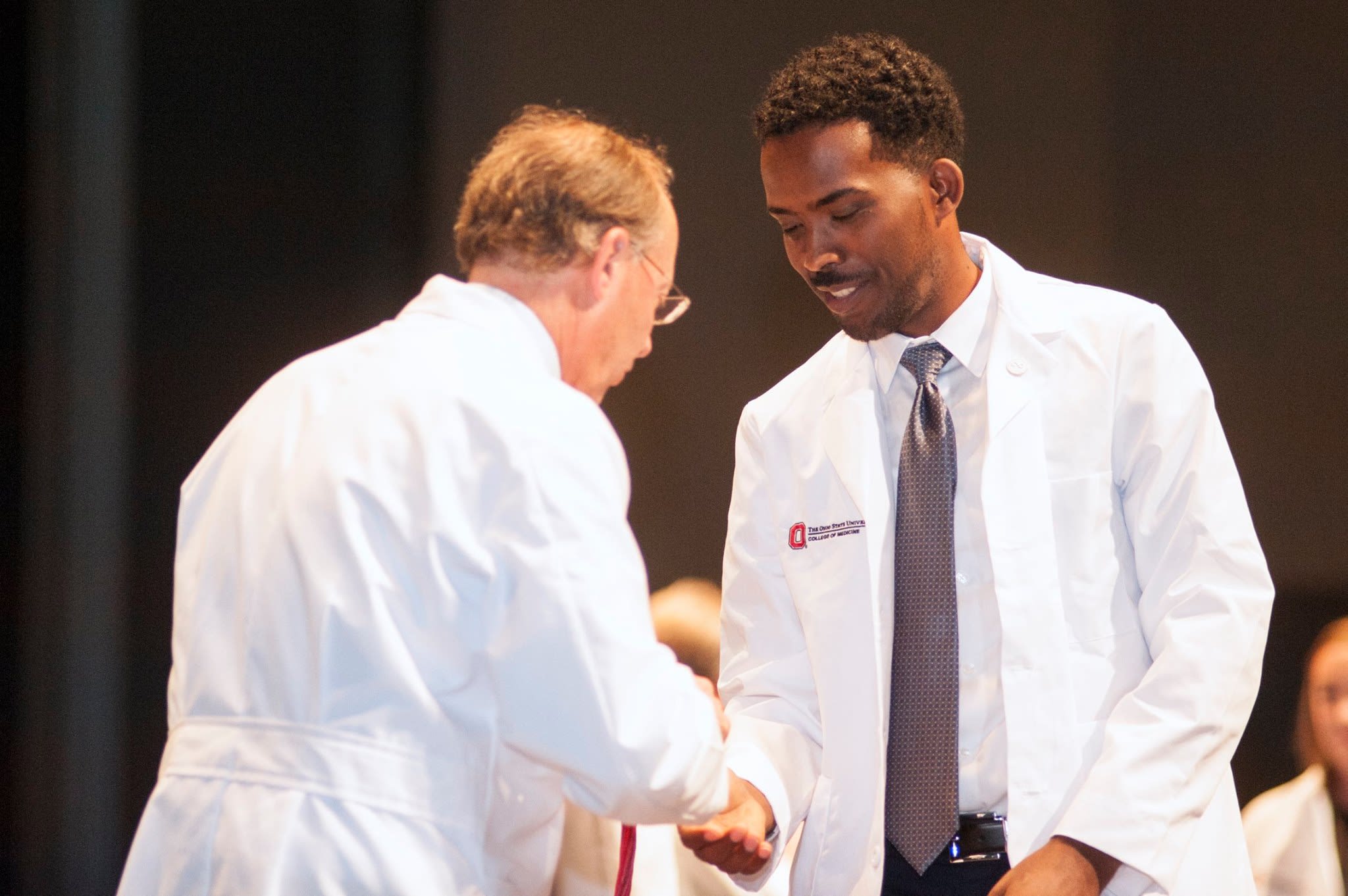 Student shaking the hand of their mentor on stage