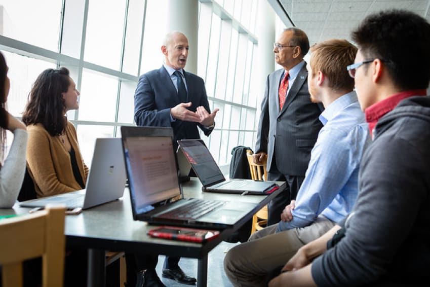 Group of students talking with UB President and a Professor.