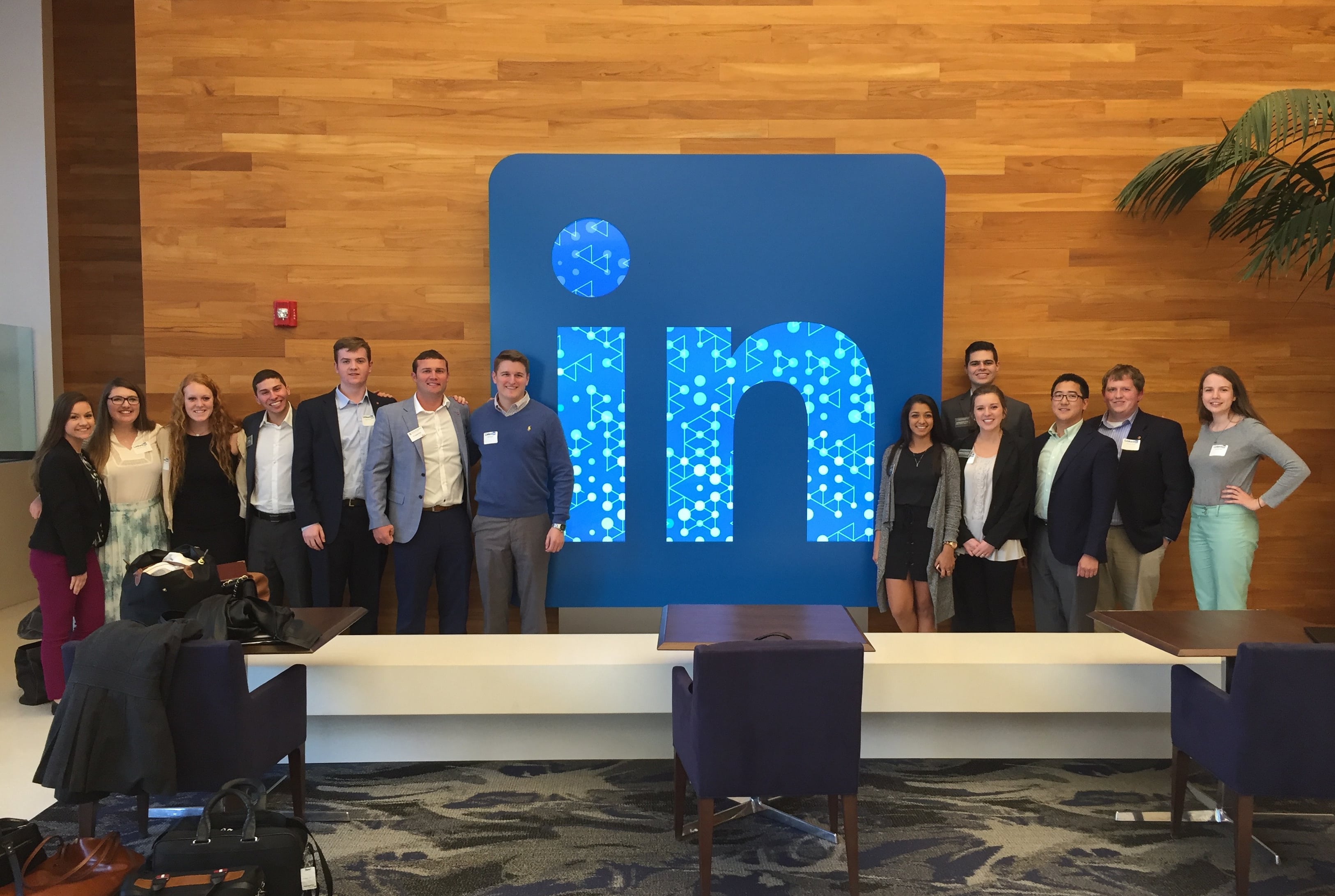 Business students stand next to a LinkedIn image on a stage