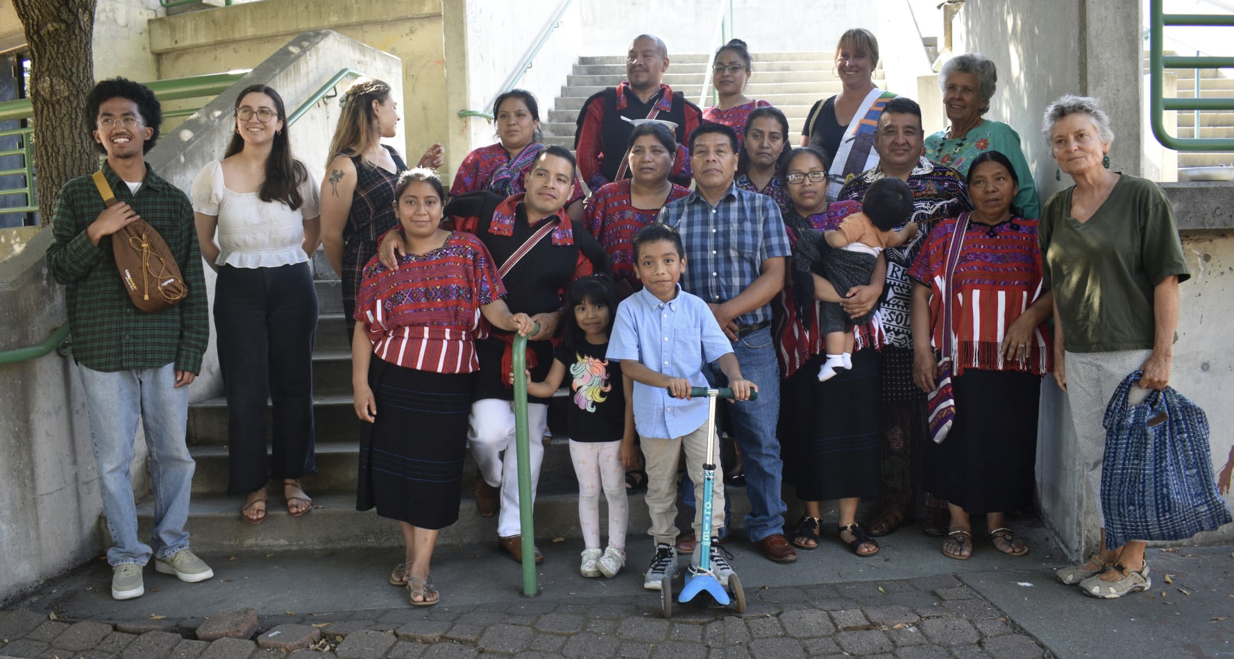 A group of students and community members gather on stairs outside after a weaving class