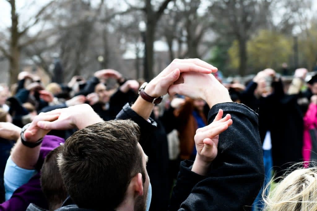 An over the shoulder shot of individuals holding their arms up in an O