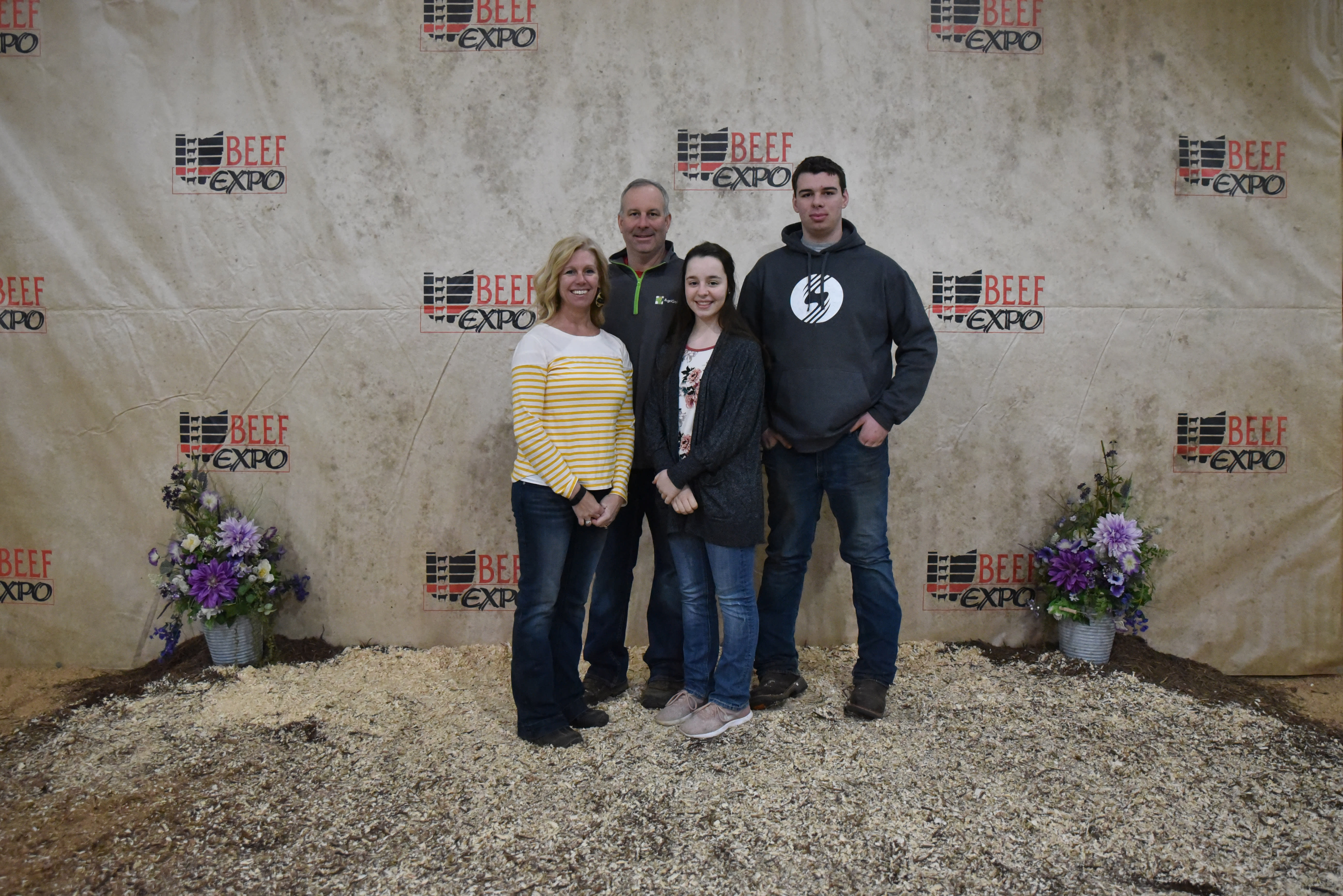 Four members of the Sutherly family standing before the Beef Expo backdrop 