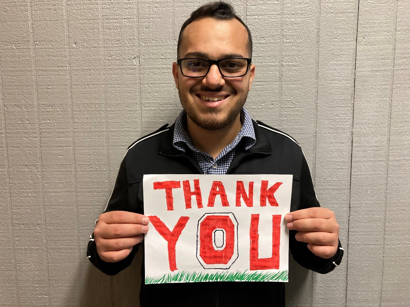 Ramzy Abukhader holding a sign that says 'Thank You.' The O is a block O