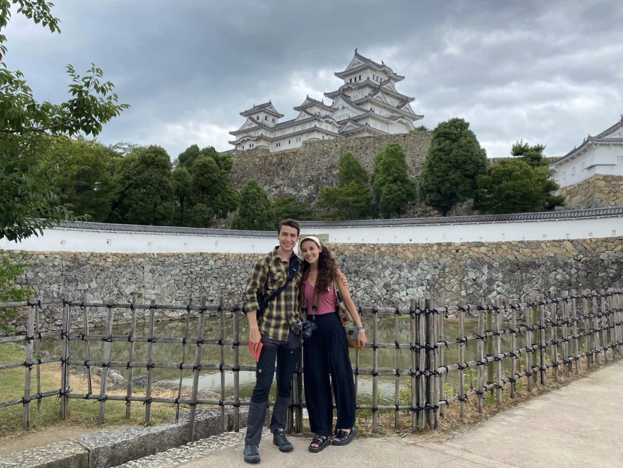 A person and person posing for a picture in front of a building

Description automatically generated