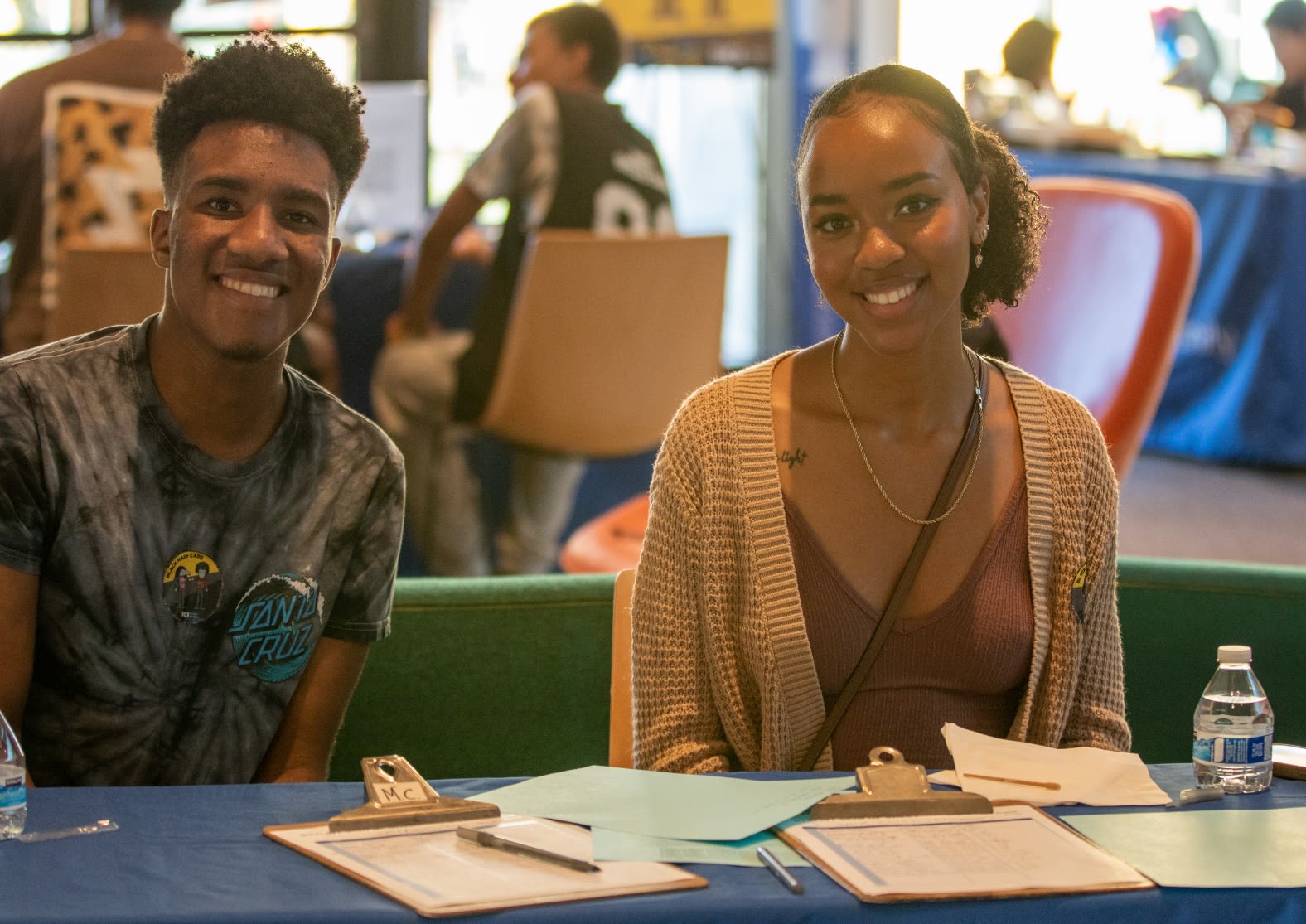 Two smiling students sitting at a table.