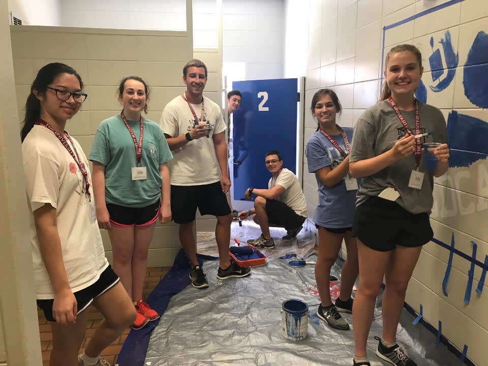 Students painting a restroom for a community project