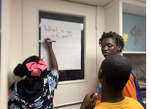 Students in a classroom writing on white board.