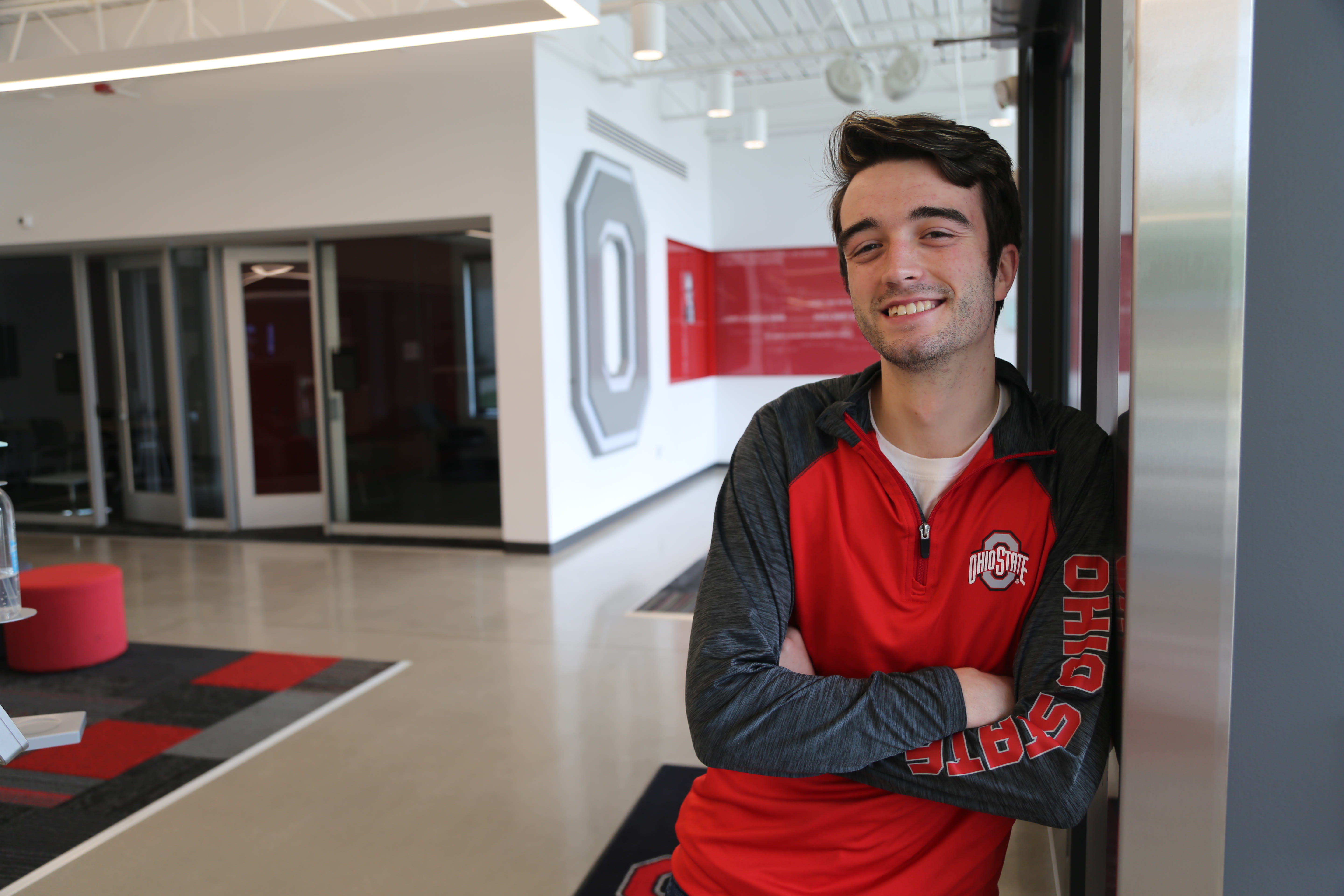 An OSU student leaning against a wall inside of a building on the Lima campus