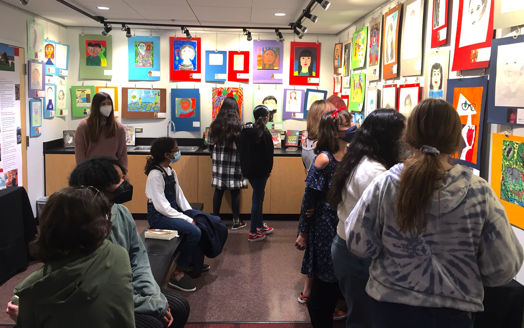 Middle school students look at self portraits of children during COVID lockdowns