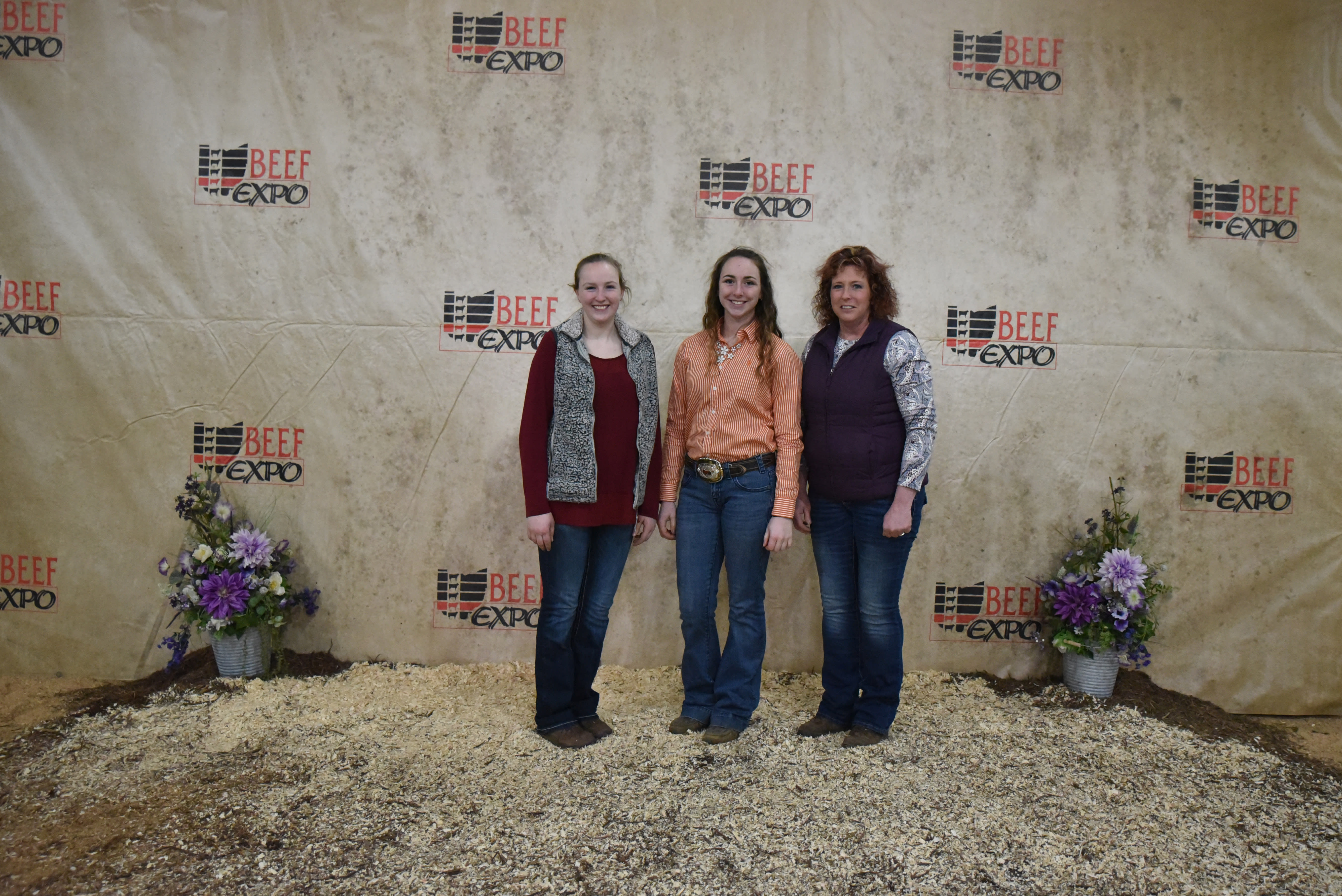 Three members of the Winter Family stand together before the Beef Expo backdrop
