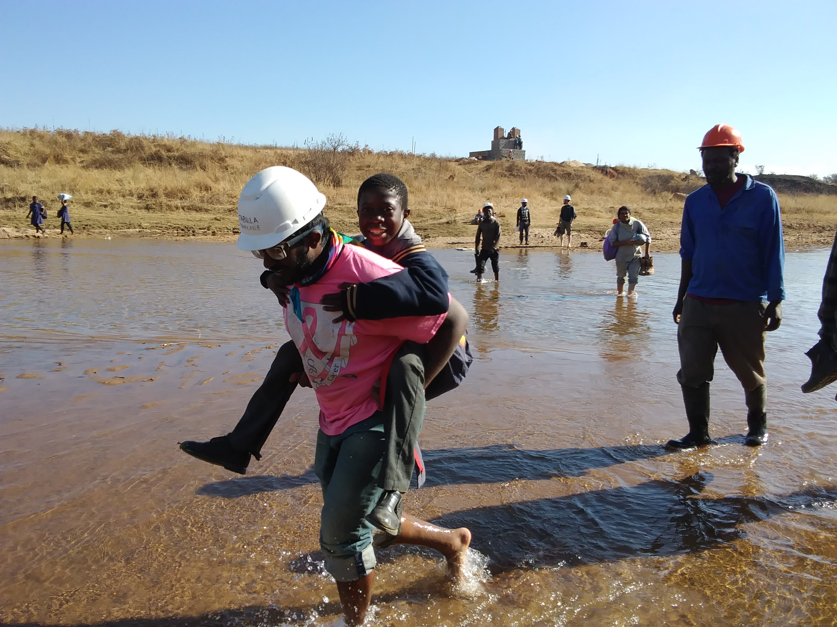 Construction Manager carrying Swazi student across river on his back