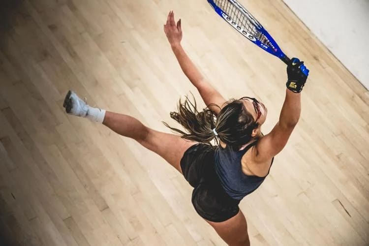 Racquetball member on court jumping to hit a ball