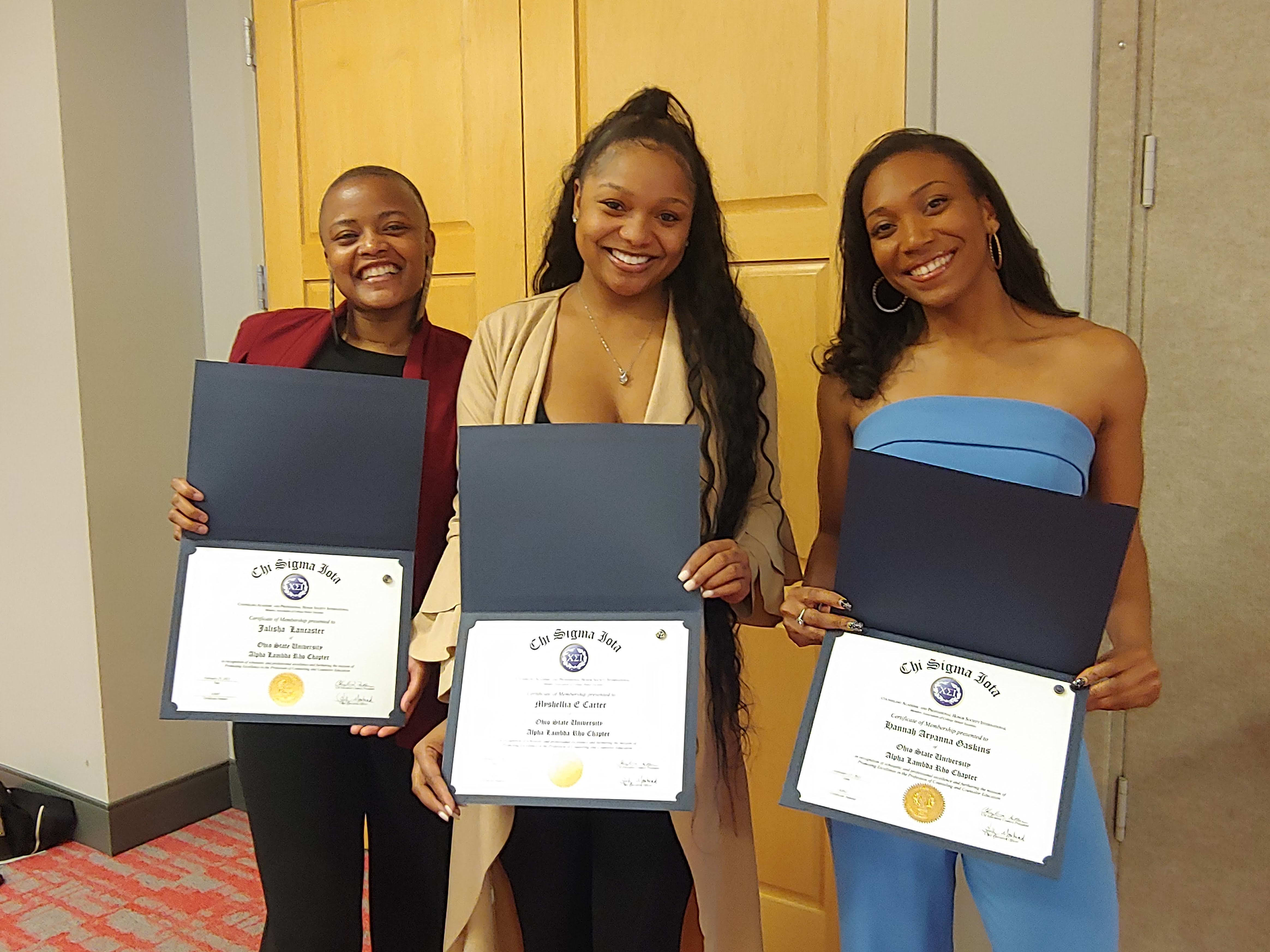 Three students holding their Honor Society certificates