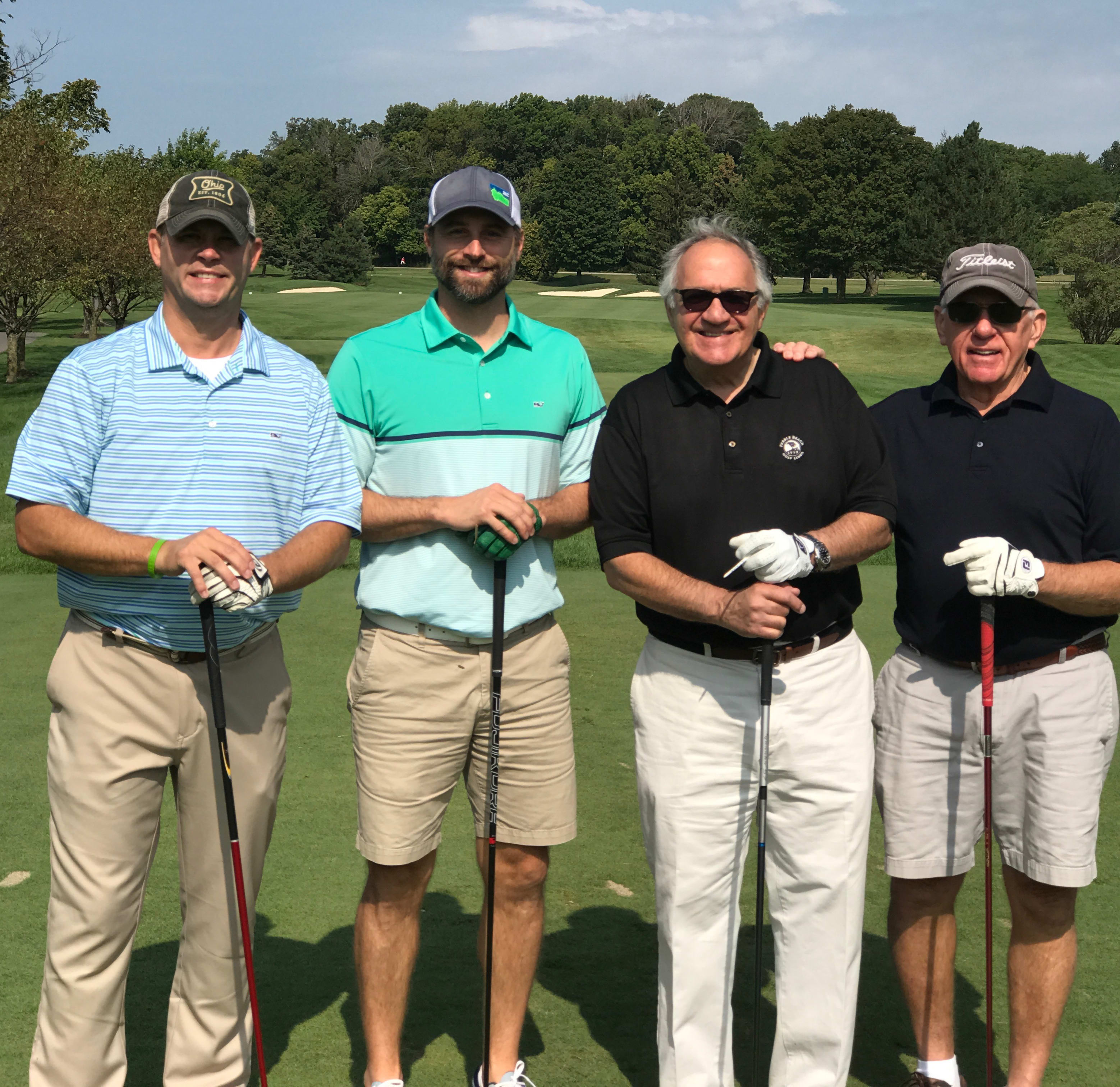 Four men stand side by side in golfing attire