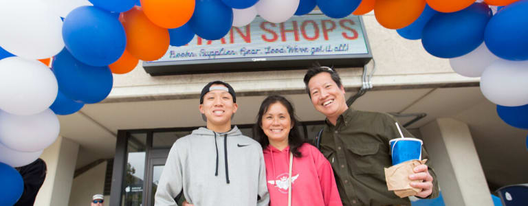 two parents next to student with arms around him