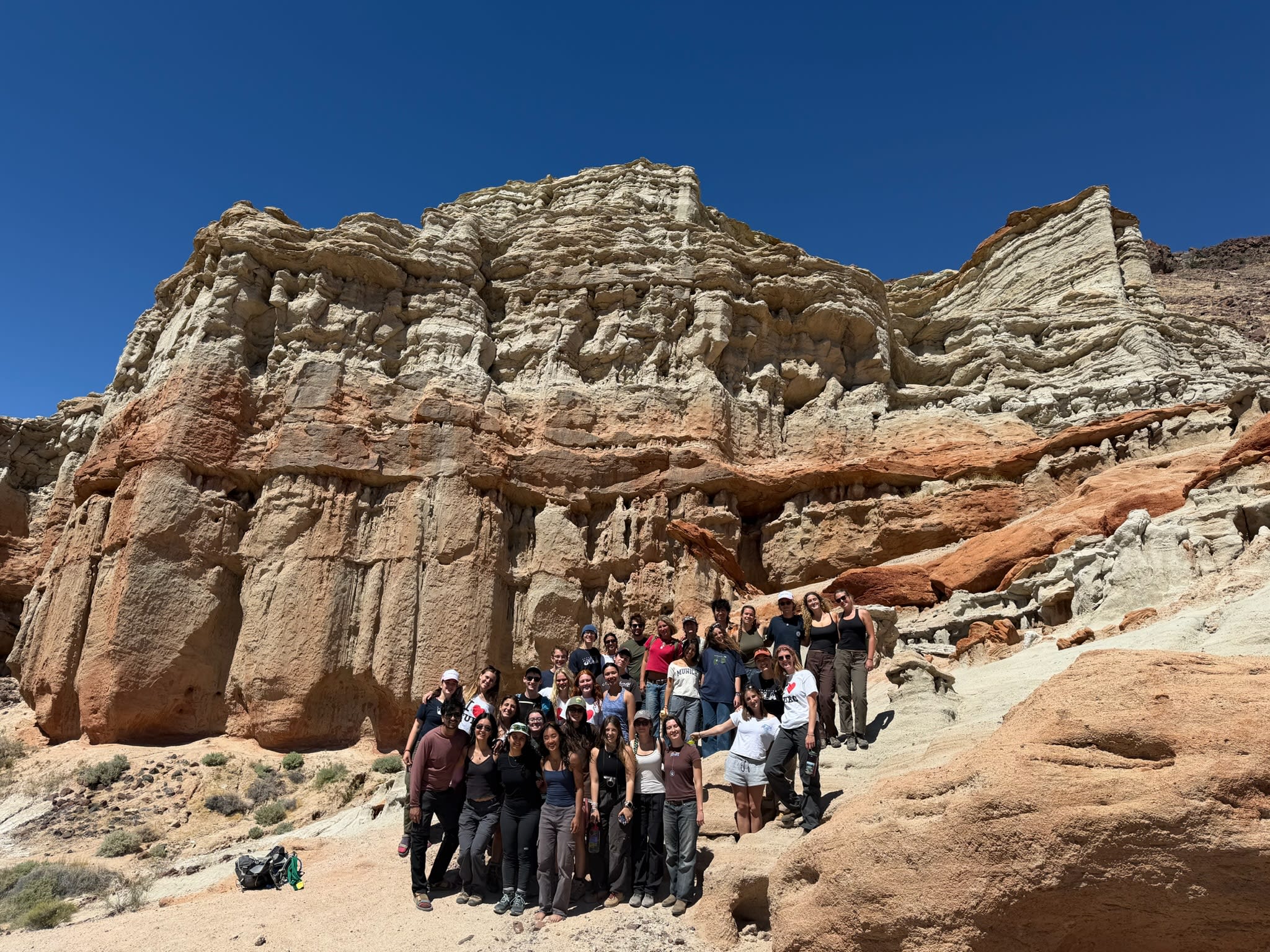 The club staff stand together smiling at the camera with red rock pillars behind them.