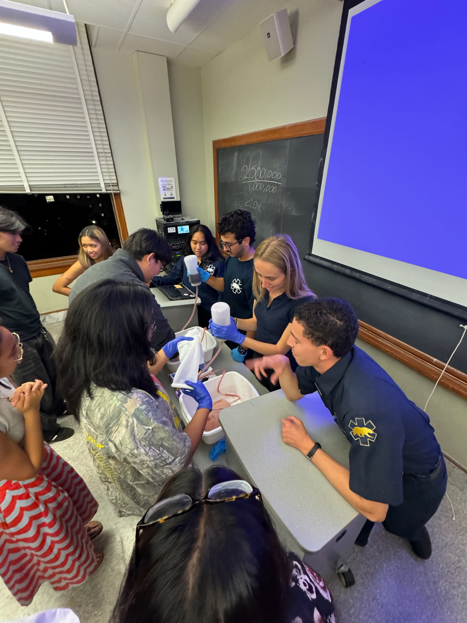 Students learn techniques on stopping bleeding at a workshop in a classroom.