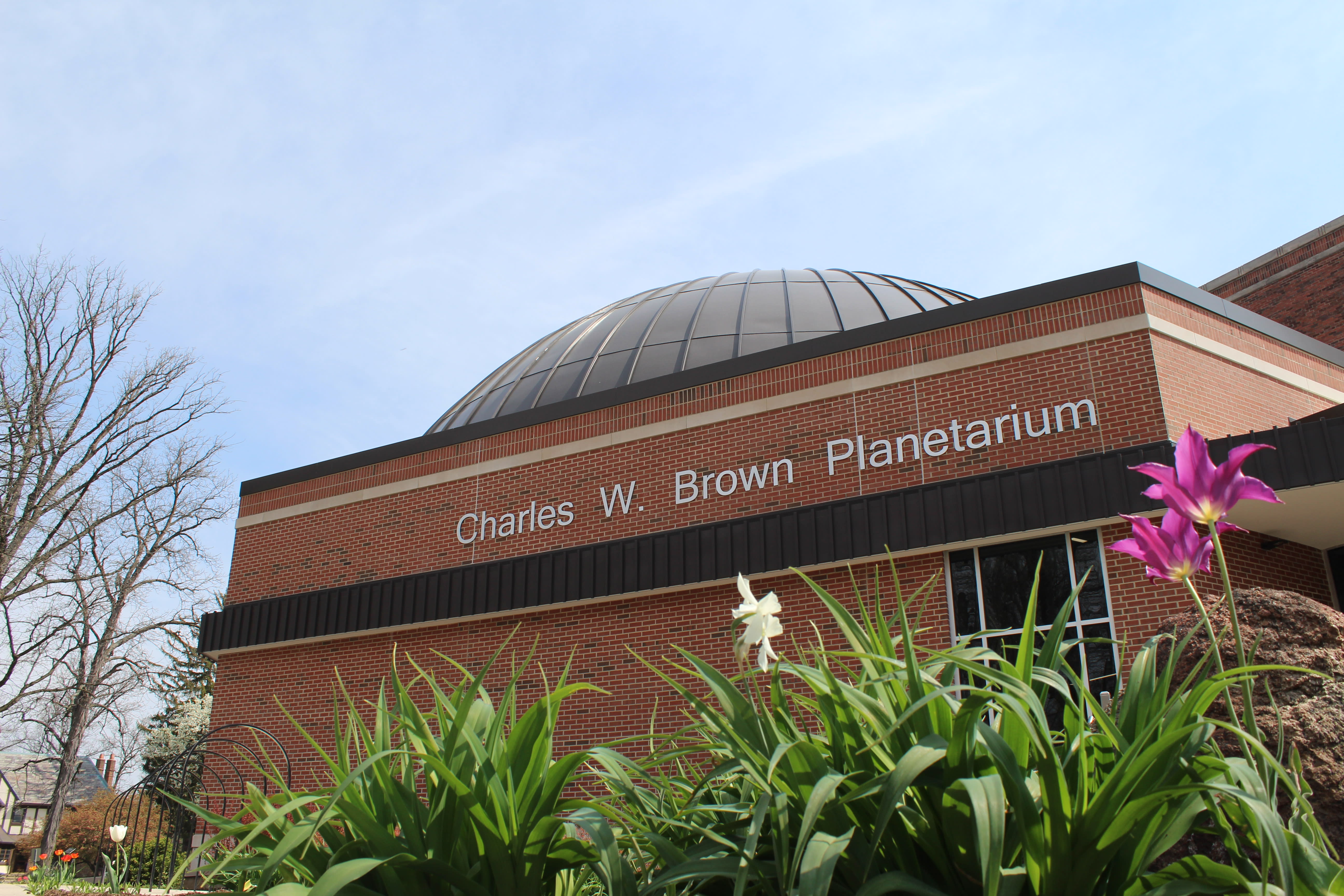 image of the exterior of the planetarium, dome building, flowers in foreground
