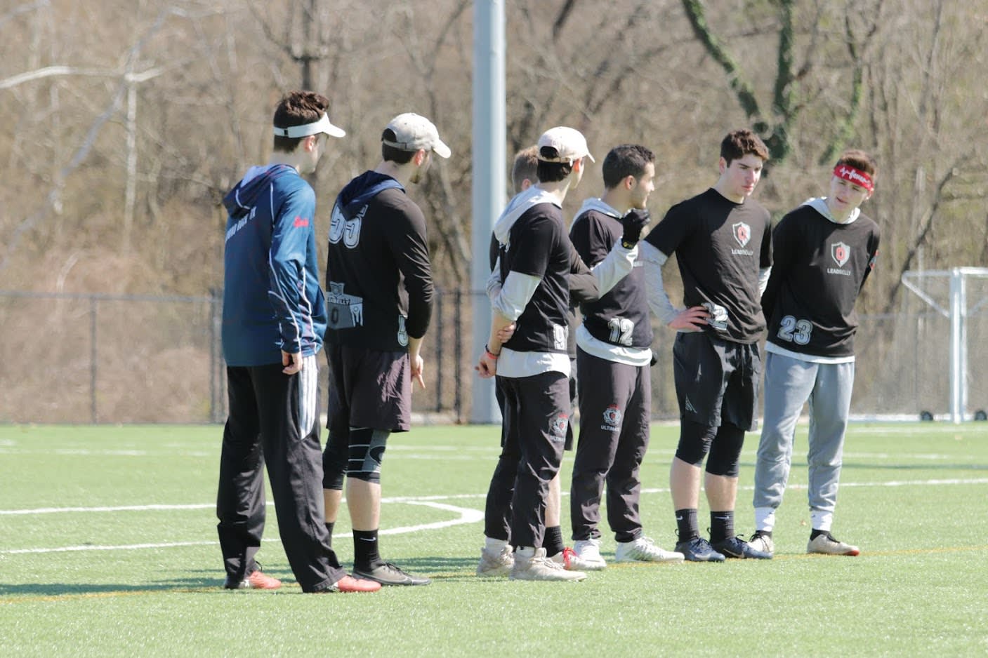 Seven team members stand around the end of a field 