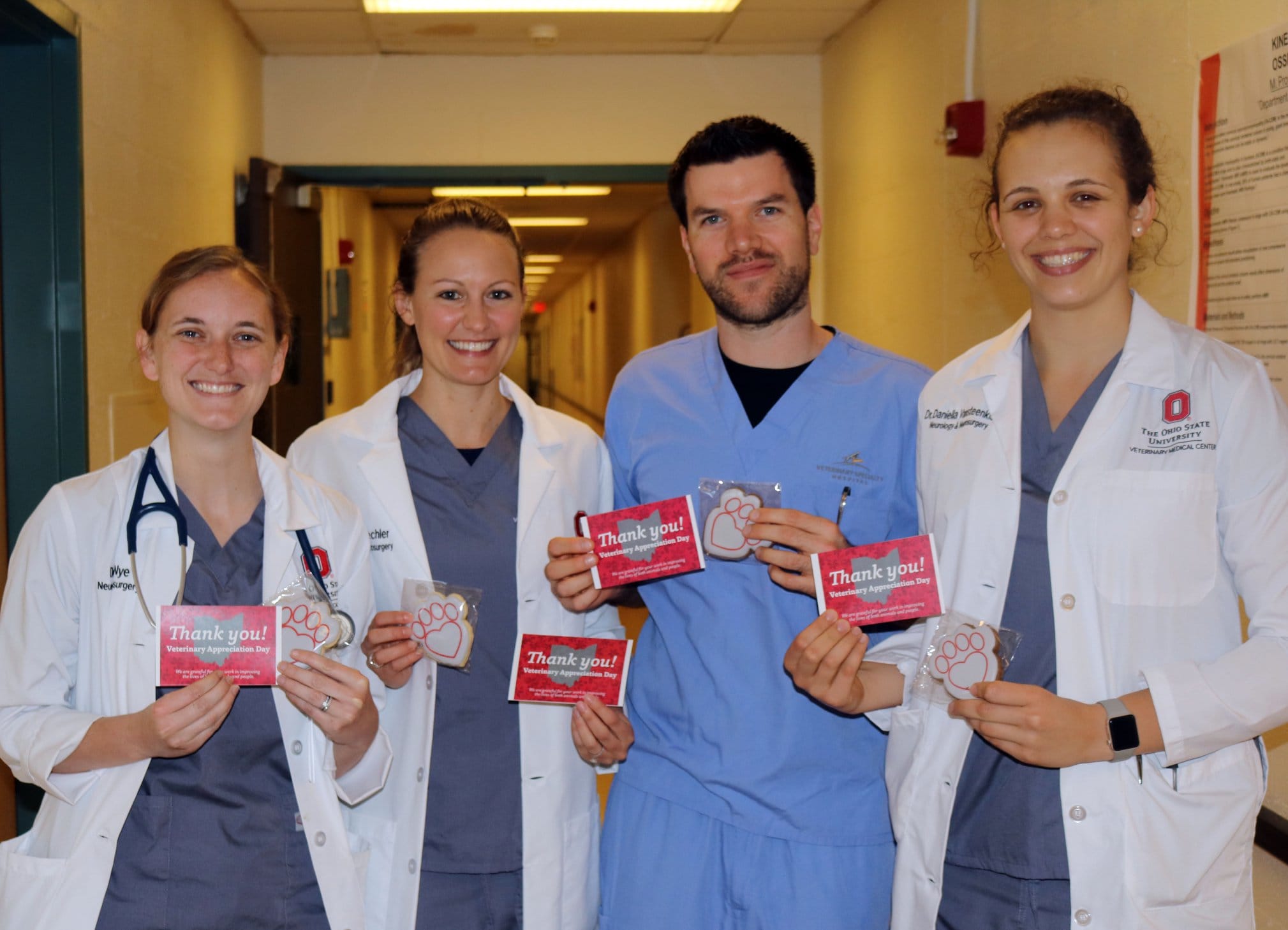 Four veterinarian students holding thank you cards with pawprint cookies