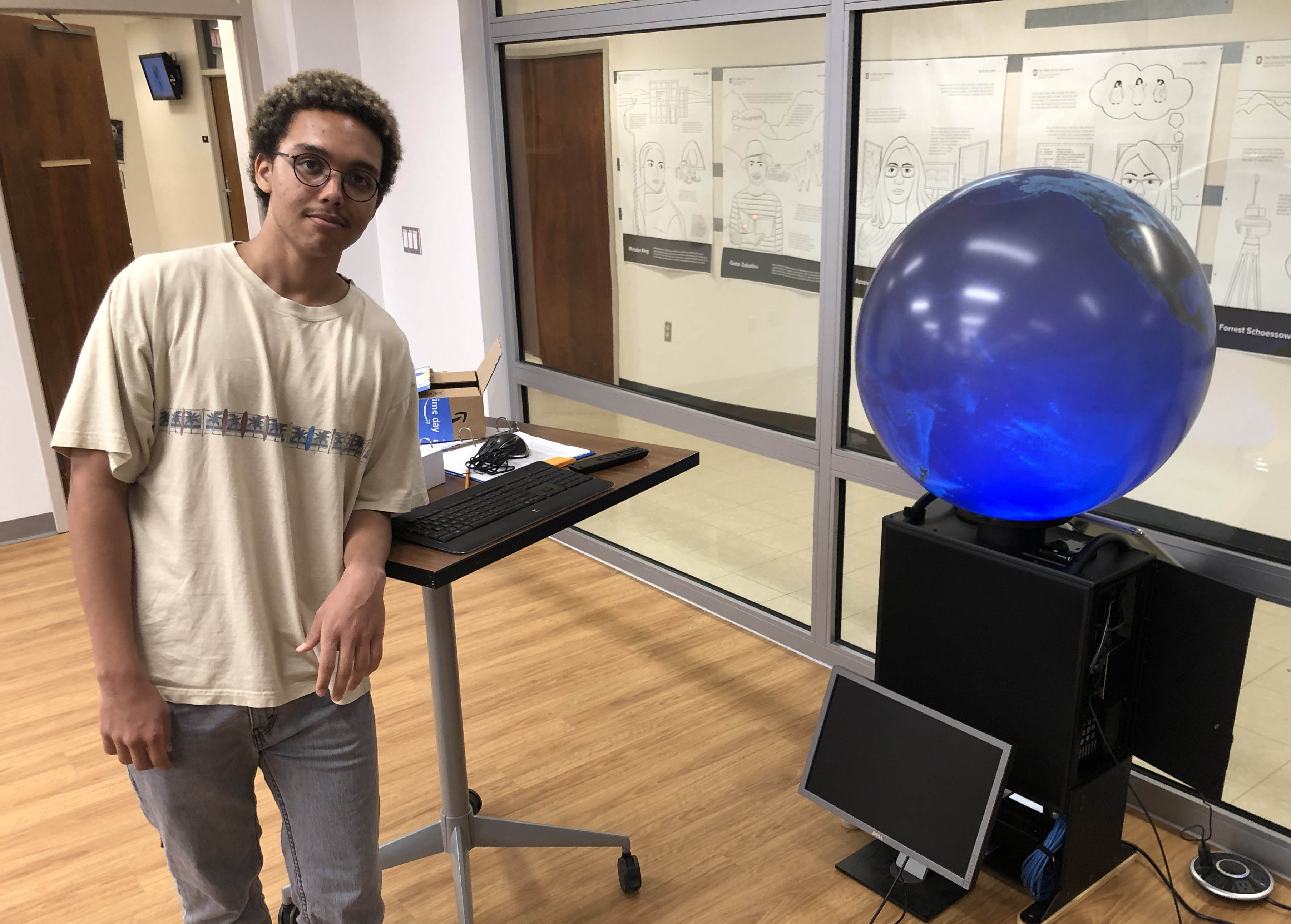 Intern posed beside a blue lit sphere