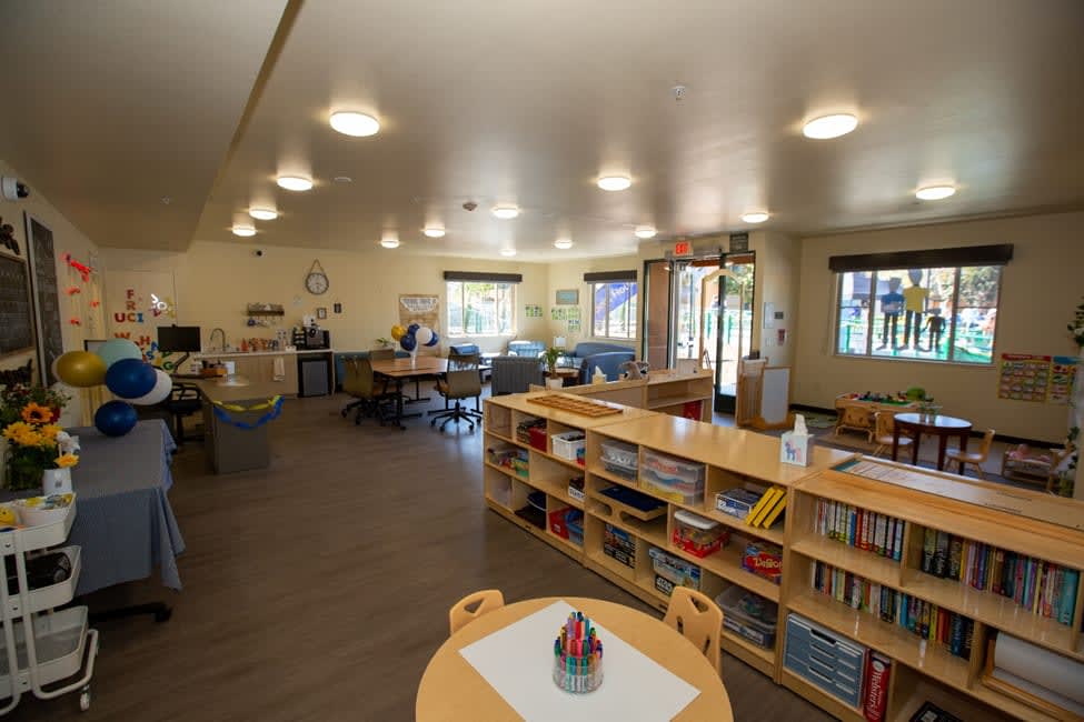 Inside the Family Resource Center. Color stations, play areas, and a bookshelf full of children's books and games.